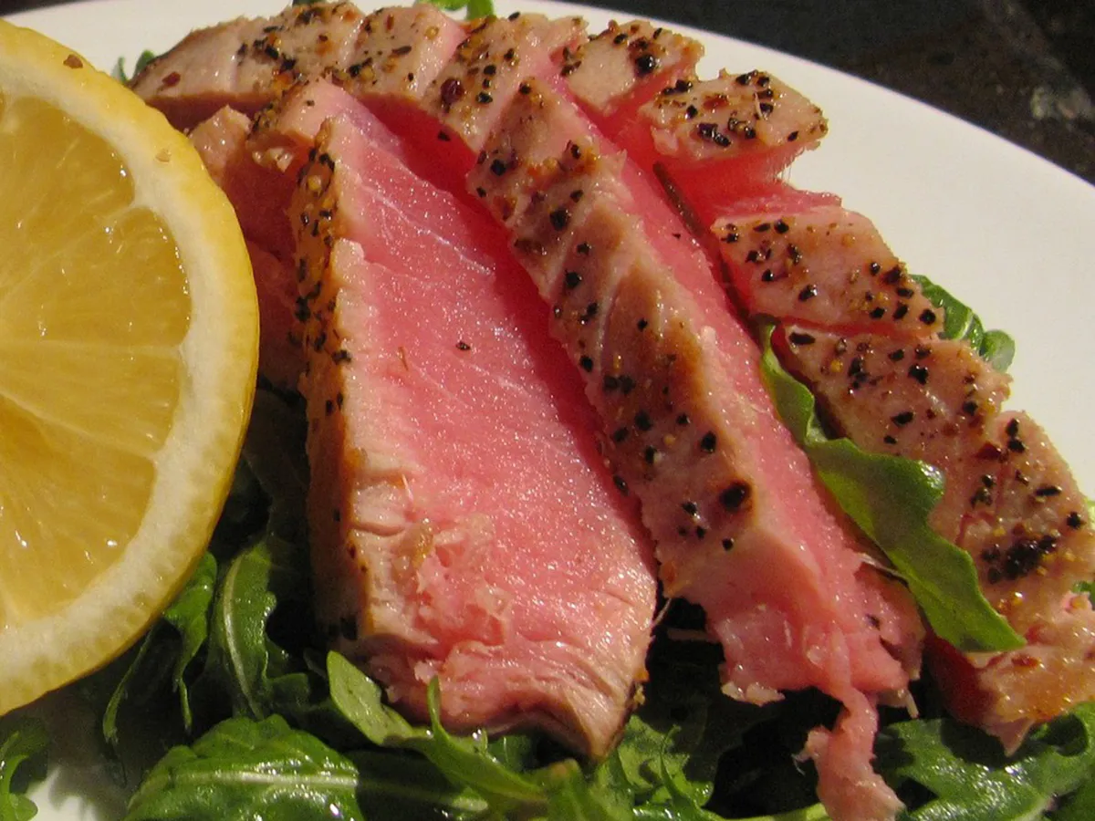 Seared pepper-crusted tuna slices over fresh arugula with lemon wedge side garnish at NIGIRI BAR JAPANESE RESTAURANT, a Japanese Restaurant in Jacksonville