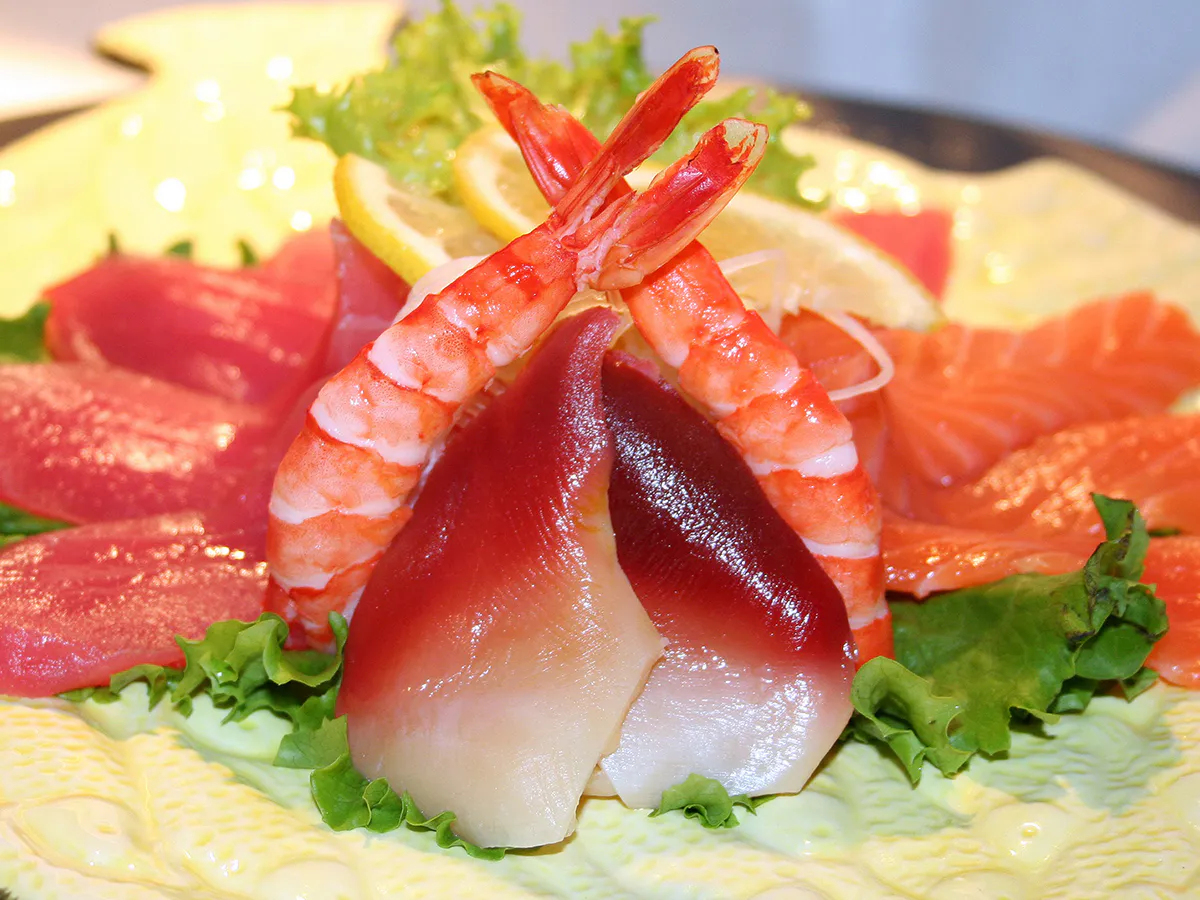 Colorful sashimi platter with shrimp, tuna, salmon and scallop arranged on leafy greens at NIGIRI BAR JAPANESE RESTAURANT, a Japanese Restaurant in Jacksonville